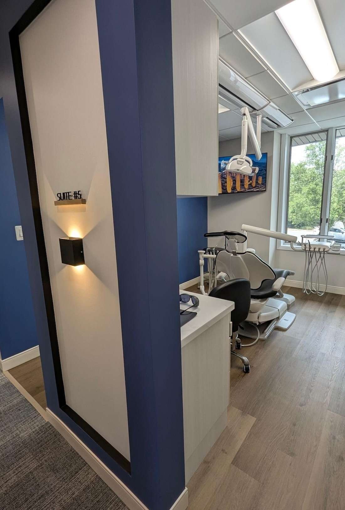 Suite #5 entrance with a blue partition wall and lit sconce